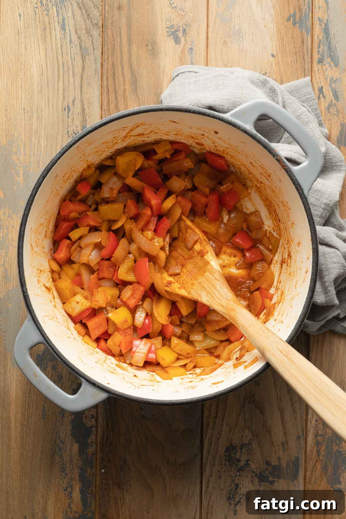 Peppers and onions being sautéed in a large pot.