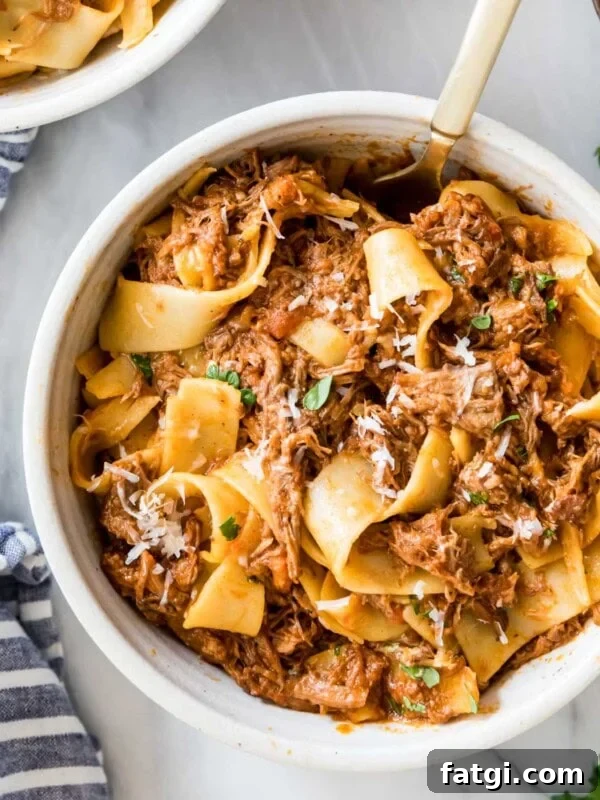 Overhead view of a bowl of beef ragu served with wide pasta noodles.