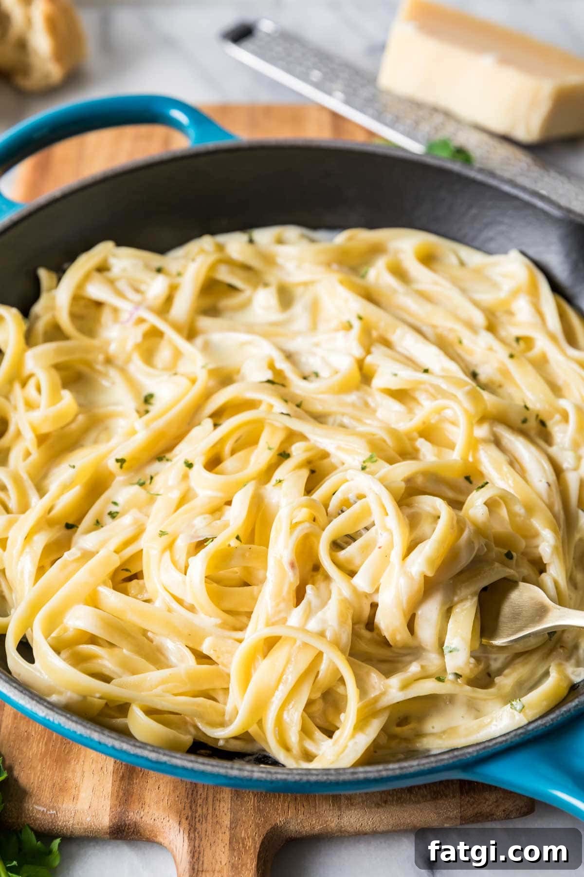 Fork twirling fettuccine pasta coated in a silky alfredo sauce.