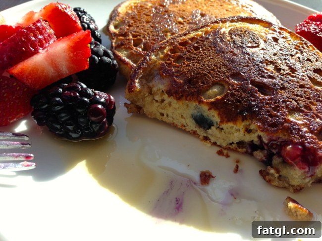 Debs Fluffy Pancake Recipe 4 Close-up of a pancake cut in half to show the fluffy interior, with syrup and fresh berries on the plate.