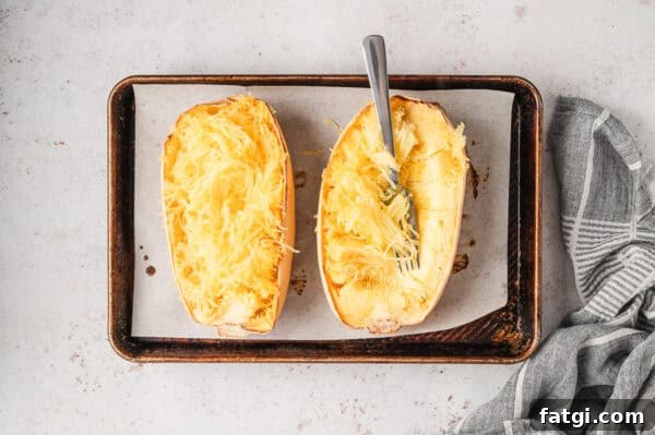 Spaghetti Squash Alfredo with Creamy Garlic Parmesan Sauce 7 2 roasted halves of spaghetti squash on baking sheet with fork