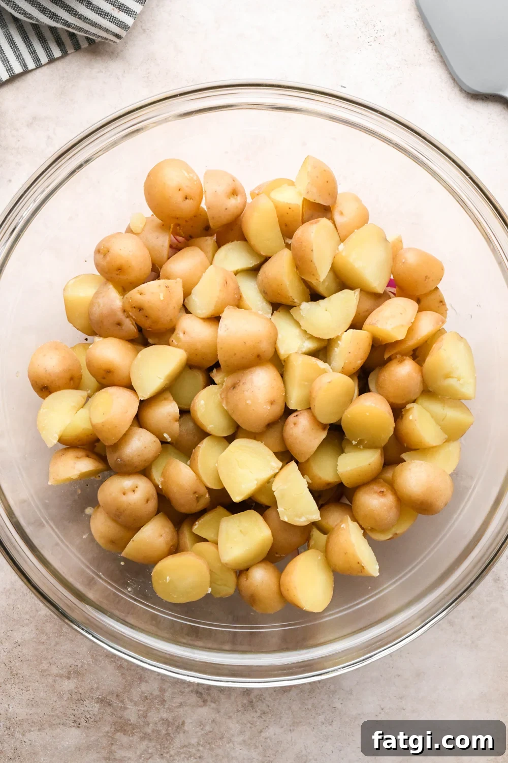 Cooked and cooled baby potatoes in the large mixing bowl with the lightly pickled red onions and the base of the dressing, before tossing to combine.