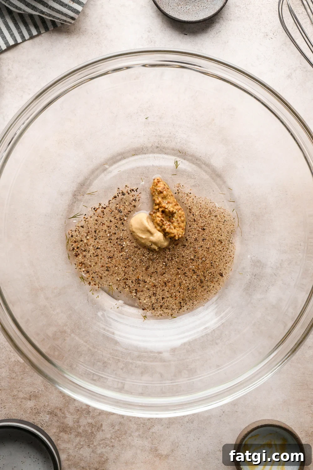 How to make Dill Pickle Potato Salad with Creamy Dill Dressing: A large glass bowl with pickle brine, white vinegar, dijon mustard, and grainy mustard, before whisking together.