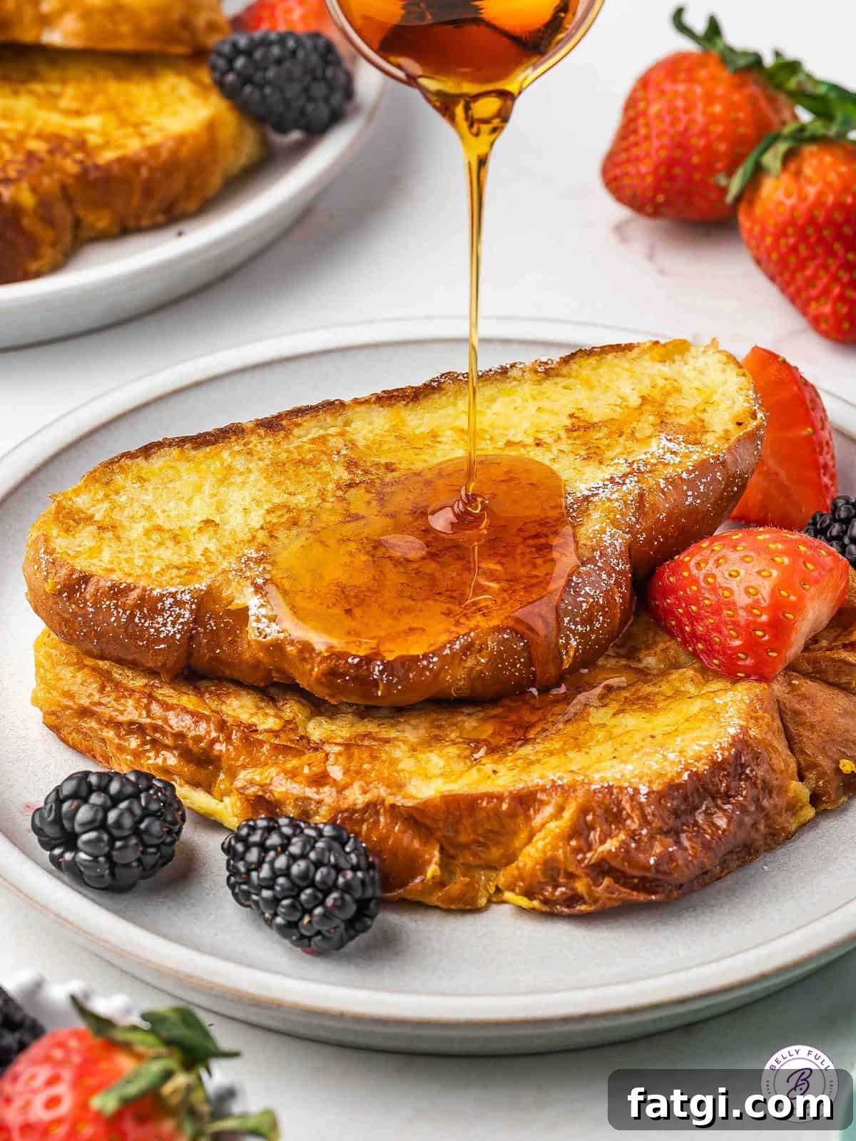 two pieces french toast with maple syrup being drizzled on top