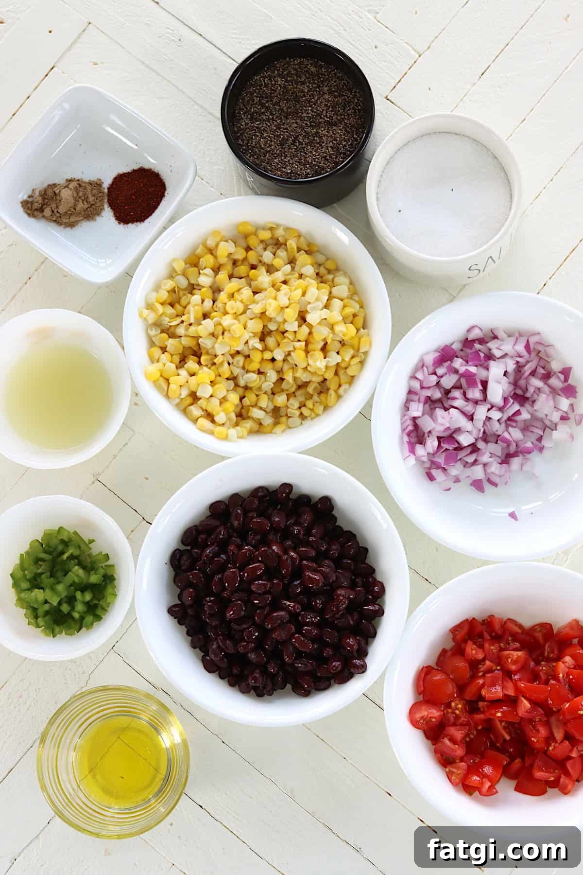 Ingredients needed for making corn and black bean salsa on a white wooden board.