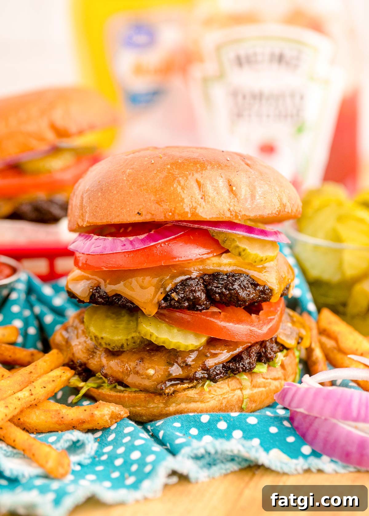 Close up of a smash burger on a blue napkin with condiment bottles in the background.