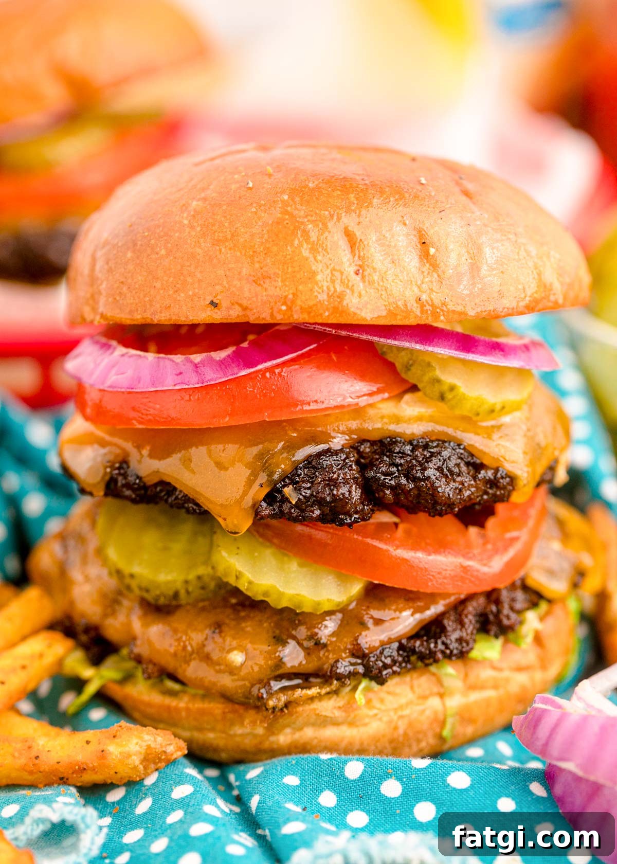 Close up of a smash burger topped with pickles, tomatoes, onions, and more.