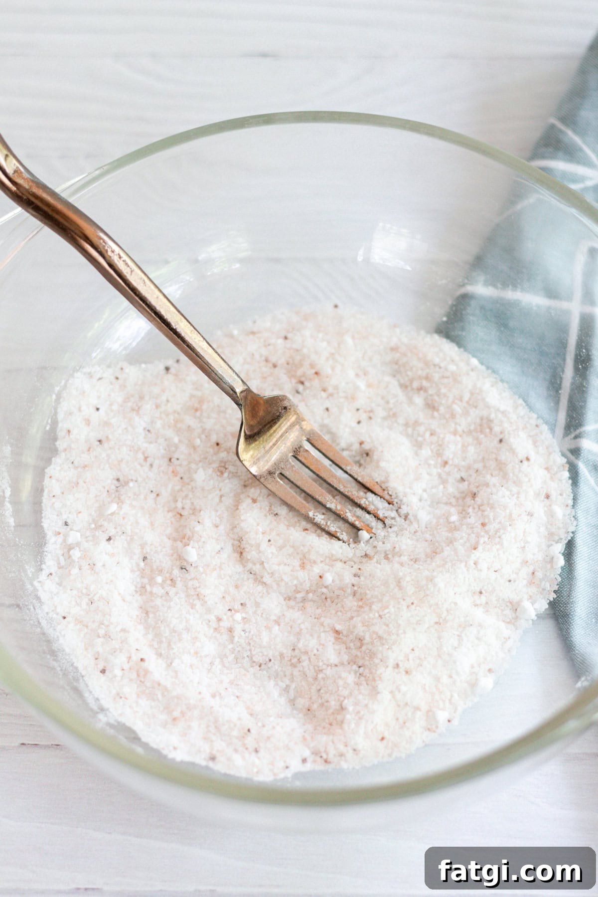 Detox Foot Soak Recipe for Tired Aching Feet 5 Dry ingredients for a detoxifying foot bath in a glass bowl, stirred well with a fork.