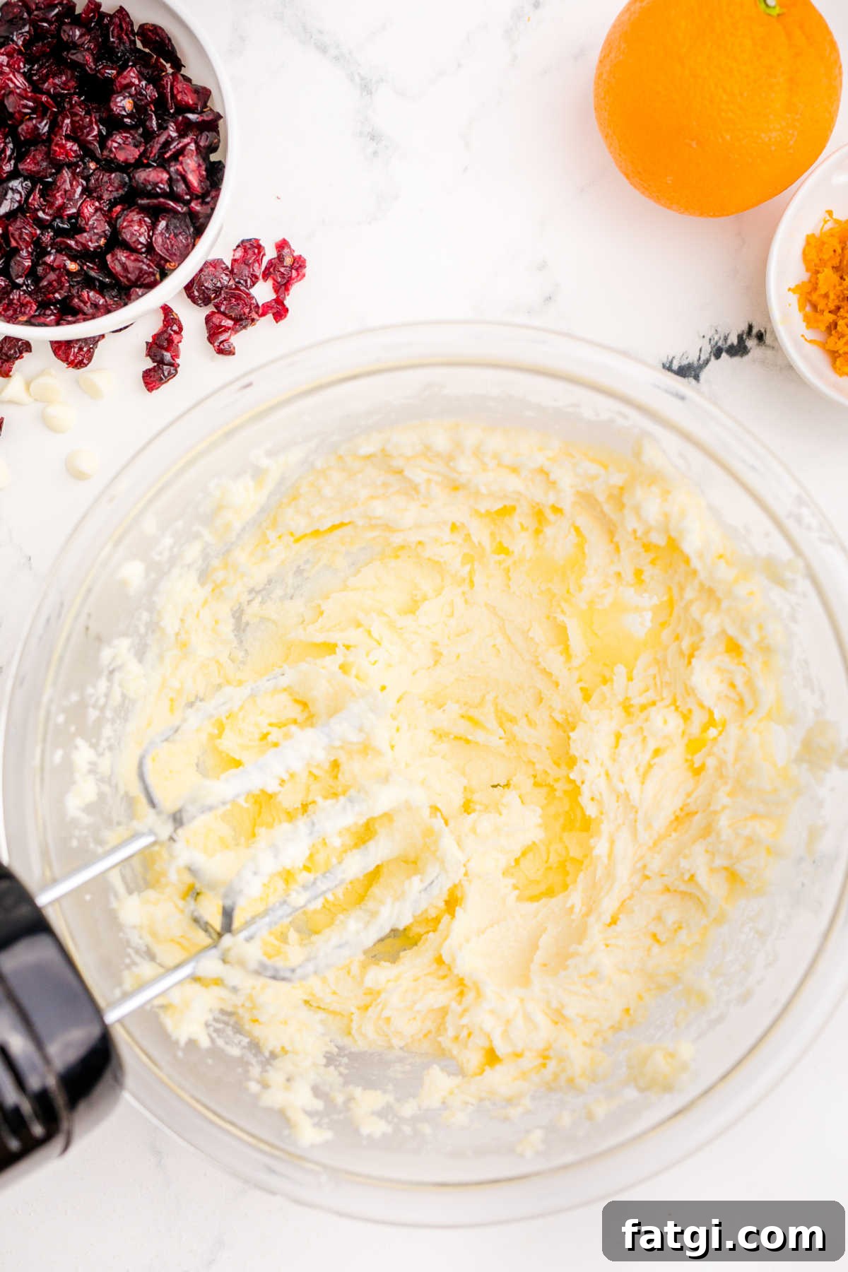 A large mixing bowl with whipped butter and sugar, with almond extract added.