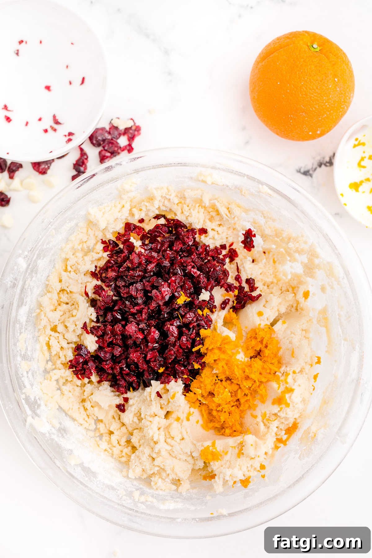 Cranberries and orange zest being added to a cookie dough.
