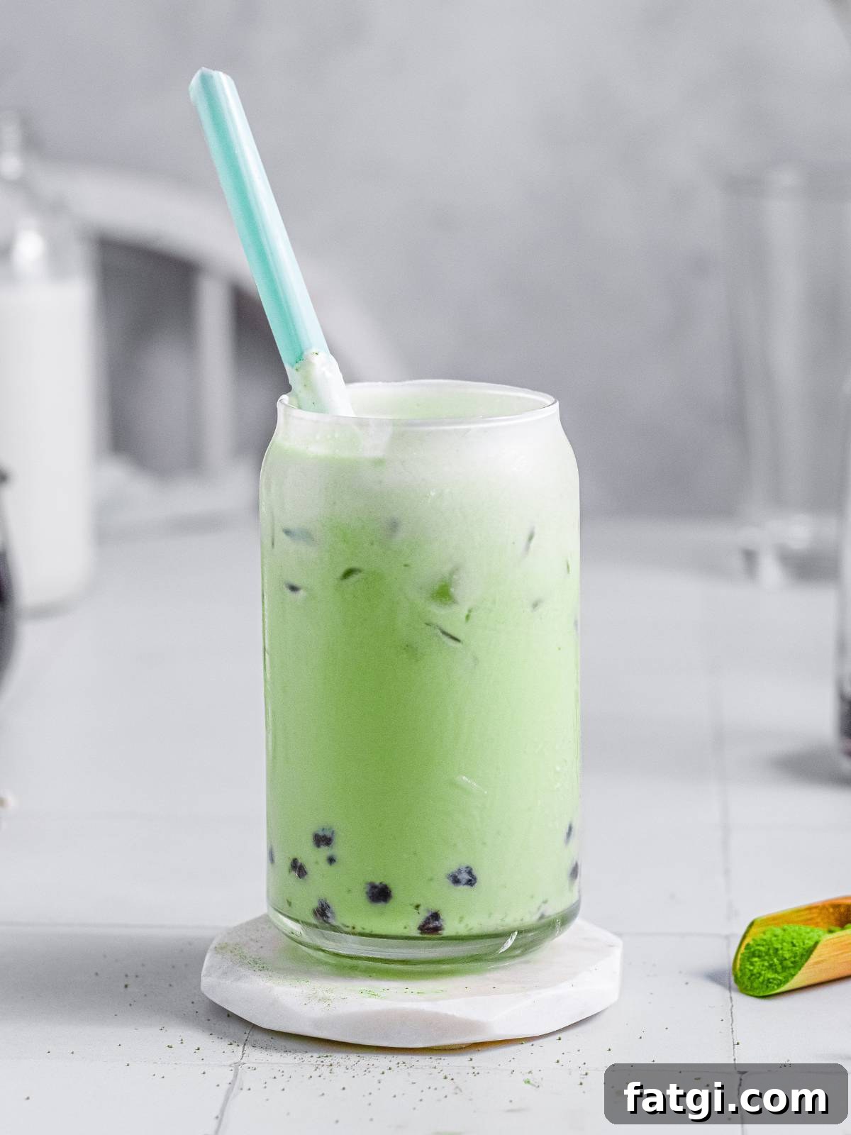 A glass of stirred matcha drink served with tapioca pearls. 