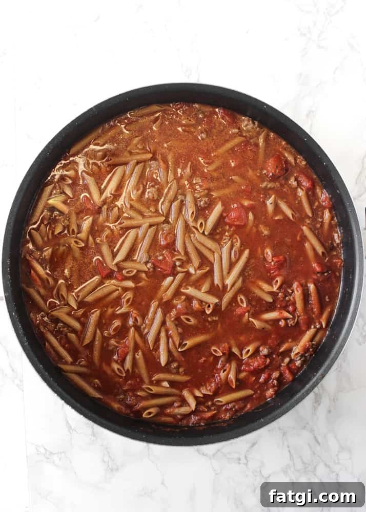 Whole-grain pasta simmering in tomato sauce for an easy one-pan baked ziti recipe