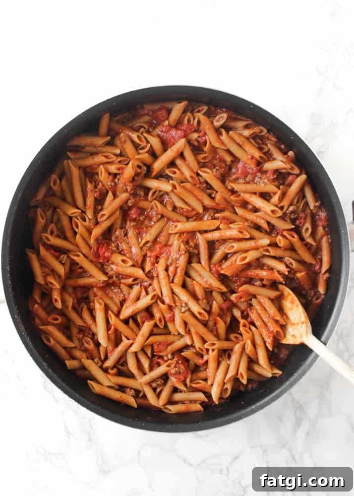 Saucy one-skillet baked ziti cooked in a pan with tomatoes and ground beef