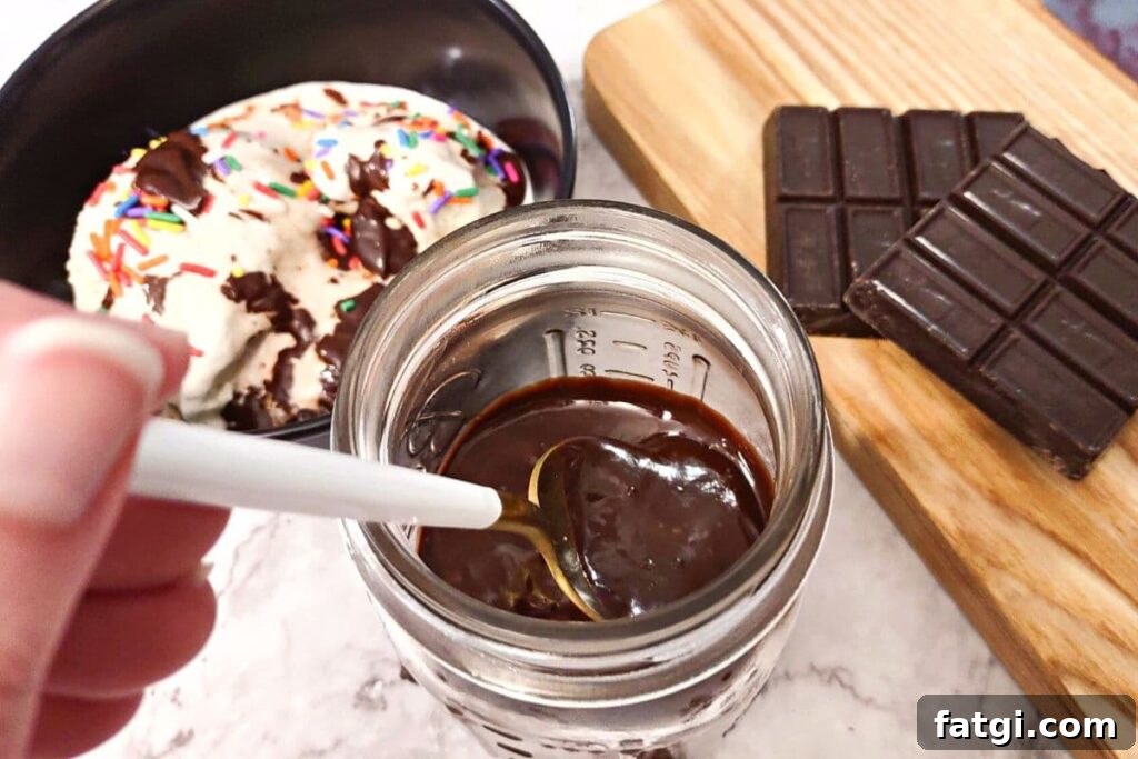 Microwave Chocolate Sauce: Homemade in Minutes 3 dipping a spoon inside a jar of melted homemade chocolate sauce