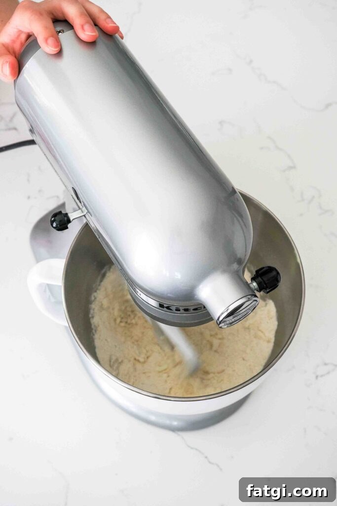 A stand mixer beats together butter, flour, sugar, baking powder, and salt.