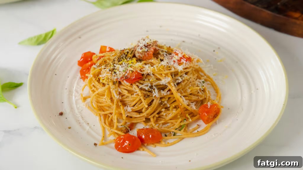 Cherry Tomato Pasta: Quick Flavorful Weeknight Dinner 3 A bed of glossy spaghetti pasta sits on a white plate. Blistered cherry tomatoes and bits of basil accent the tangled noodles.