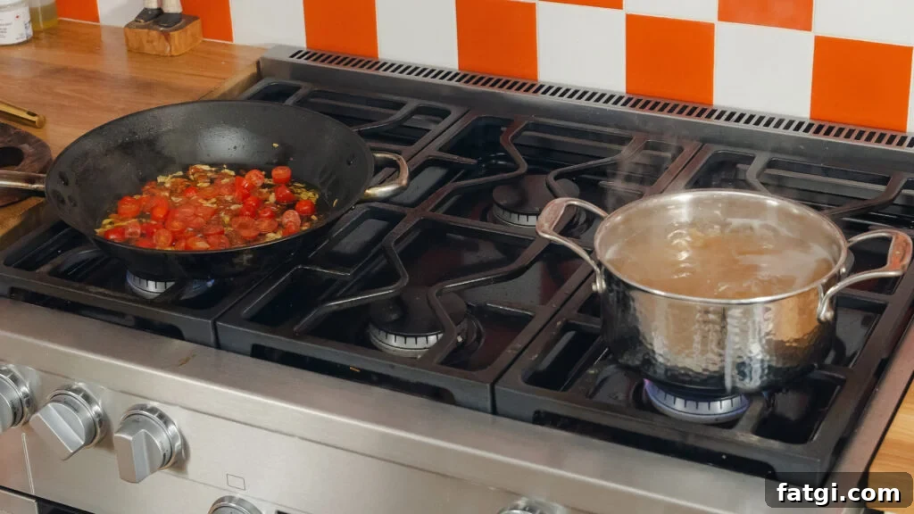 Cherry Tomato Pasta: Quick Flavorful Weeknight Dinner 5 Tomatoes set blistering in a pan, and next to it a deep pot of spaghetti cook over a propane stove.