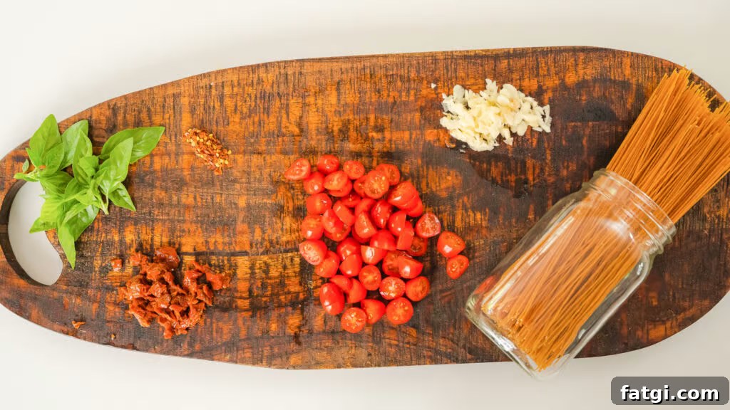 Cherry Tomato Pasta: Quick Flavorful Weeknight Dinner 6 Top down shot of ingredients for a vegetarian pasta recipe, basil, sundried tomatoes, cherry tomatoes, garlic and dried spaghetti.