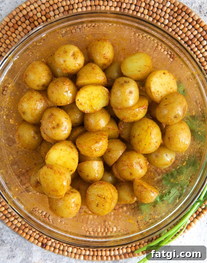 baby potatoes in a mixing bowl being tossed with cornstarch spice blend