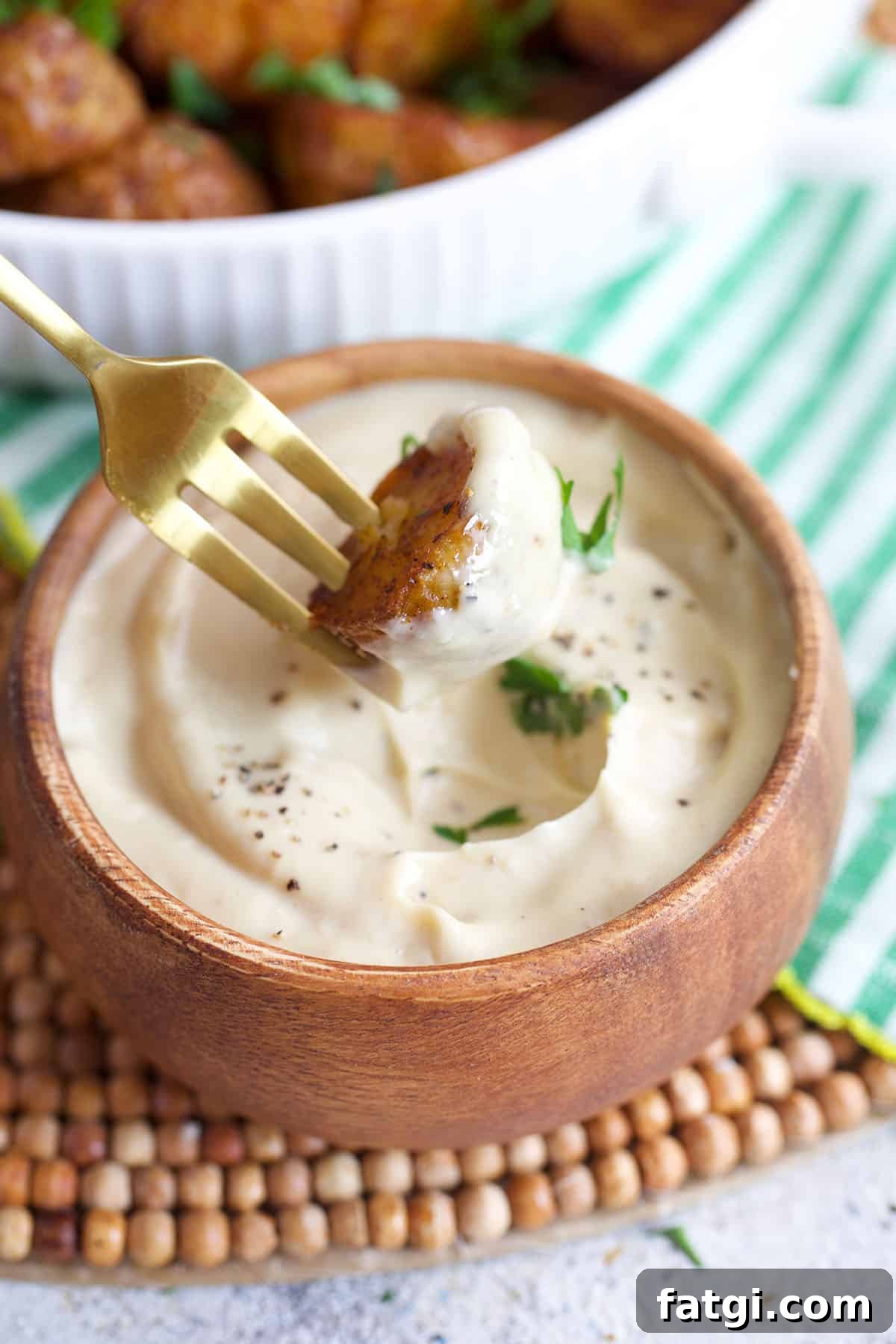 Air Fryer Roasted potato on a fork being dipped into a bowl of aioli