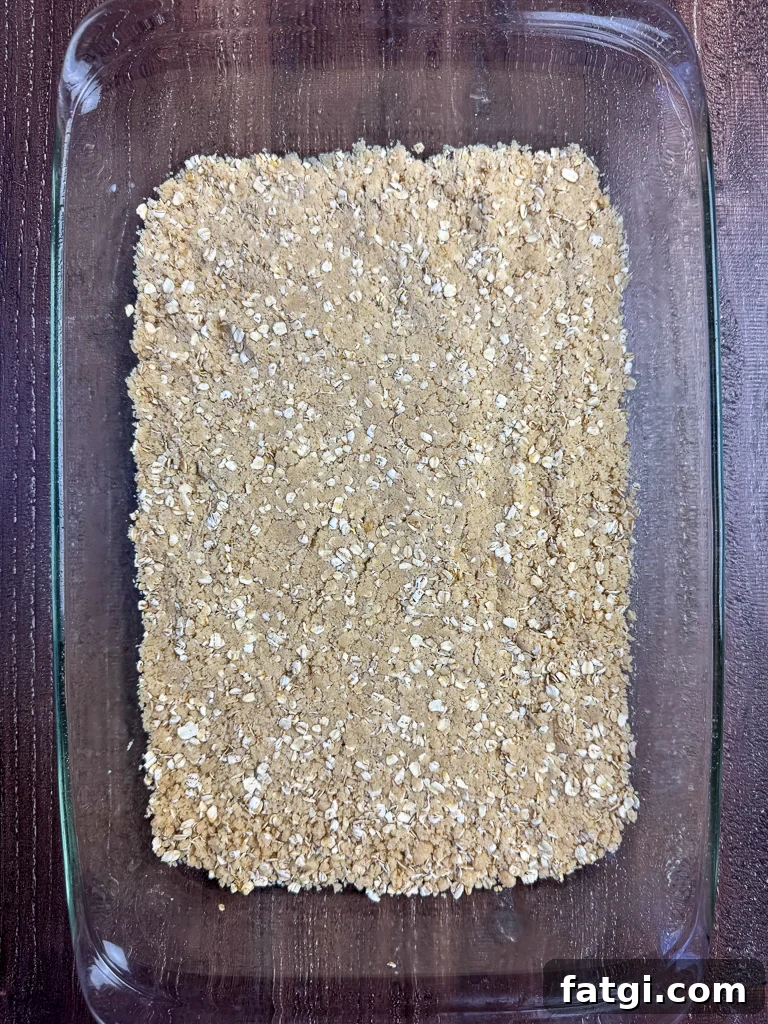 Base layer of a simple oatmeal mixture patted flat in the bottom of baking dish to make fruit bars.