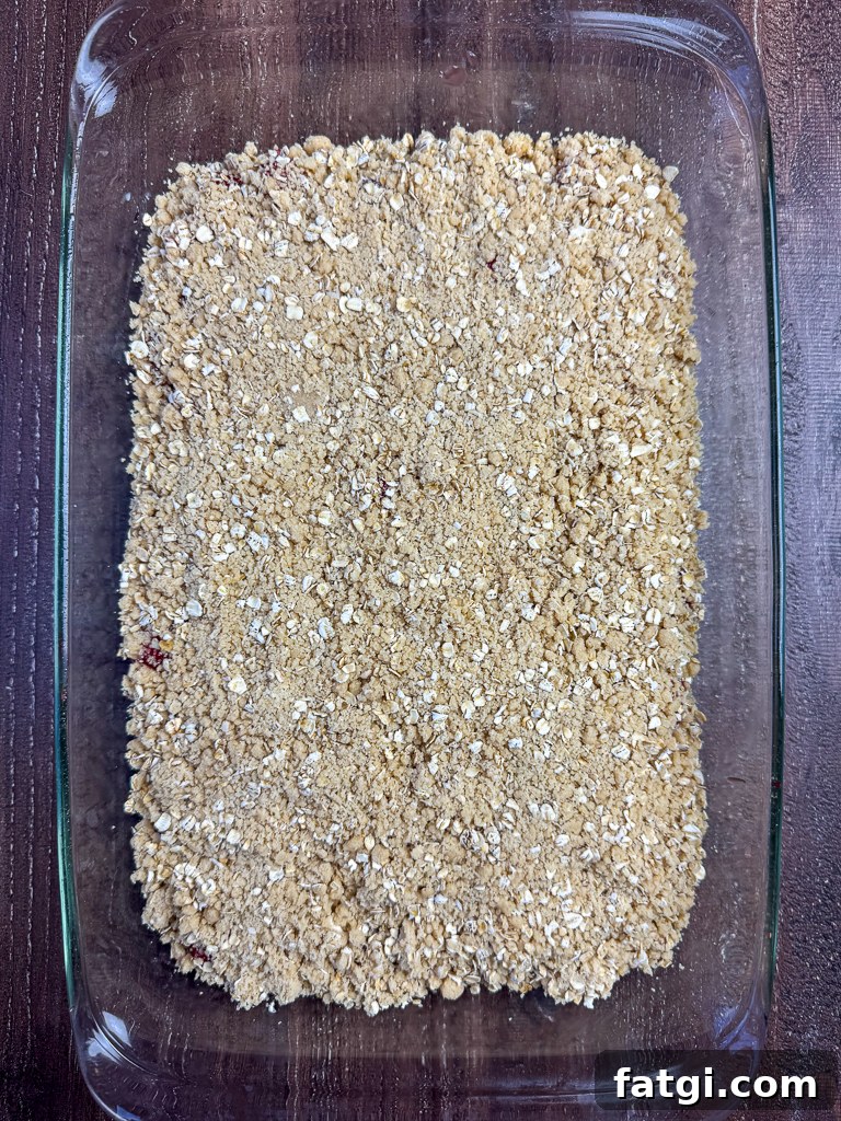 Oatmeal mixture spooned on top of fruit bars in a glass 9 x 13" pan.