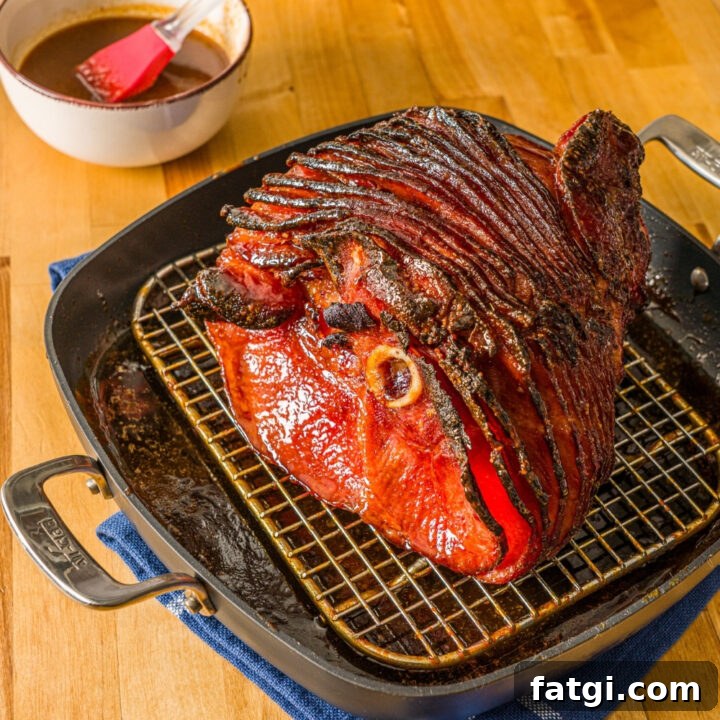 Spiral Ham with Pineapple and Brown Sugar Glaze 13 A baked glazed spiral ham in a roasting pan lined with a rack. The pan is on a wooden counter with a blue cloth napkin and small bowl of glaze with a basting brush.