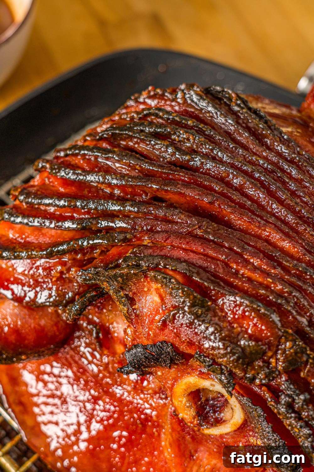 Spiral Ham with Pineapple and Brown Sugar Glaze 3 A close up of a glazed spiral ham in a roasting pan lined with a rack.