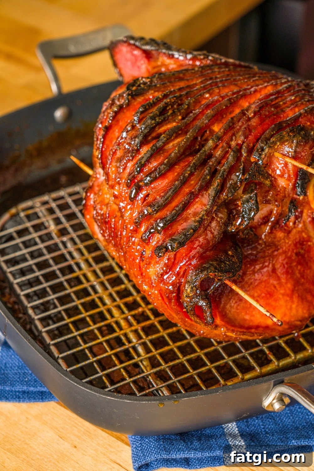 Spiral Ham with Pineapple and Brown Sugar Glaze 10 A whole glazed spiral ham on a roasting pan with a rack. The ham is sliced with toothpicks in the center.