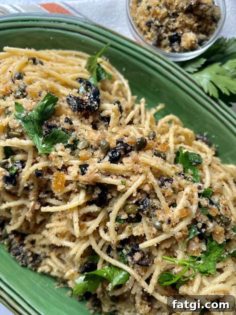 St Joseph's Pasta in green platter with parsley garnish and small bowl of breadcrumbs in background.