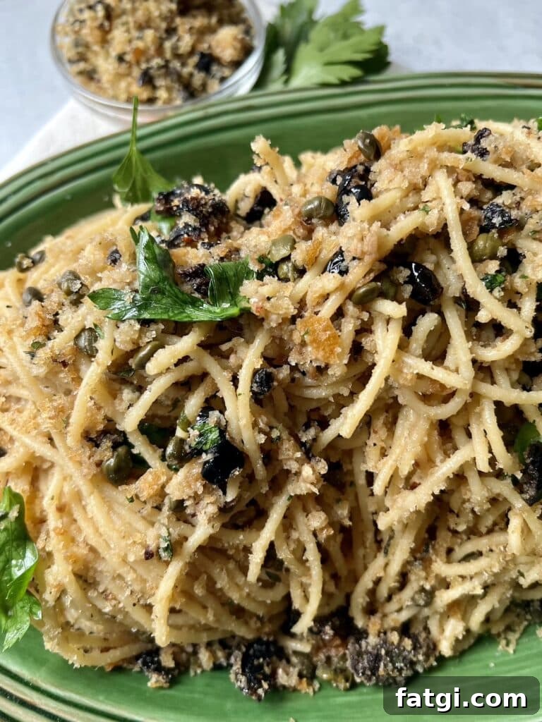 St Joseph's Pasta in green platter with parsley garnish and small bowl of breadcrumbs in background.