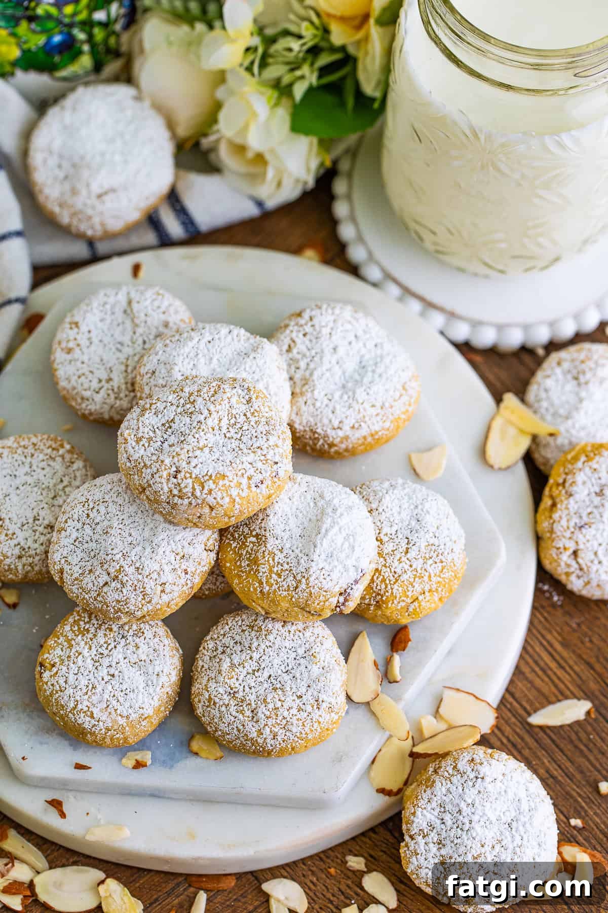 Overhead image of almond cookies dusted with powdered sugar beside a glass of milk