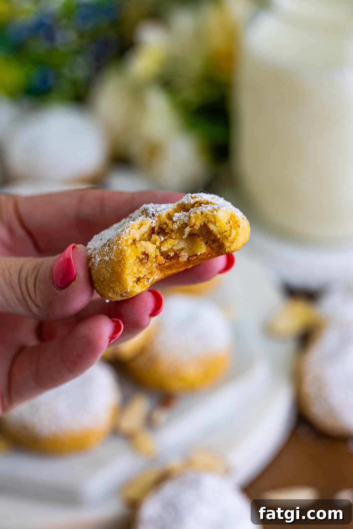 Final almond cookie with a bite taken out, held by the recipe author