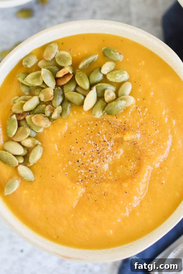 A bowl of butternut squash soup next to a spoon.