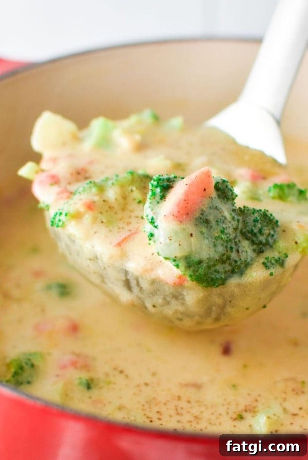 A ladle filled with Boursin broccoli cheese soup coming out of a red pot