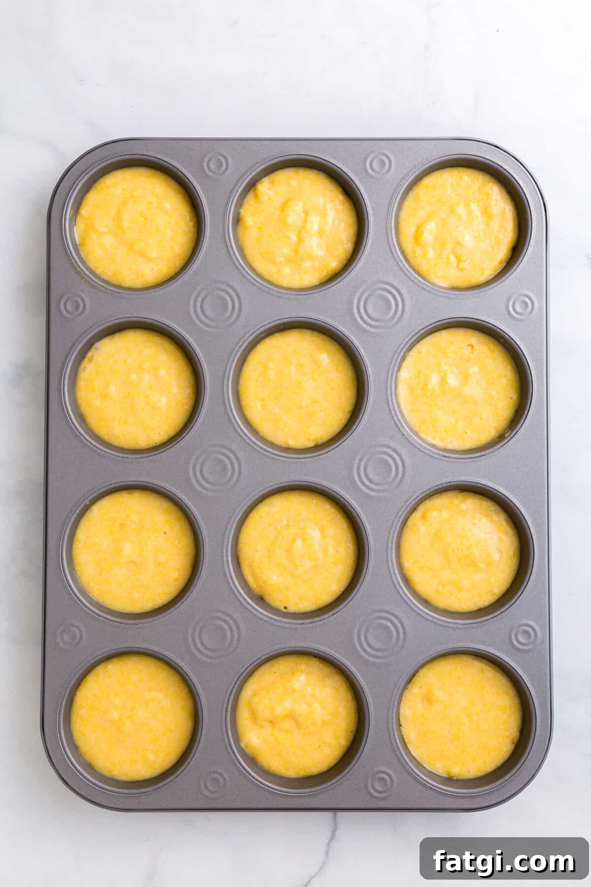 Homemade Corn Muffins with Honey Butter Recipe 6 corn muffin batter in a 12 count muffin tin.