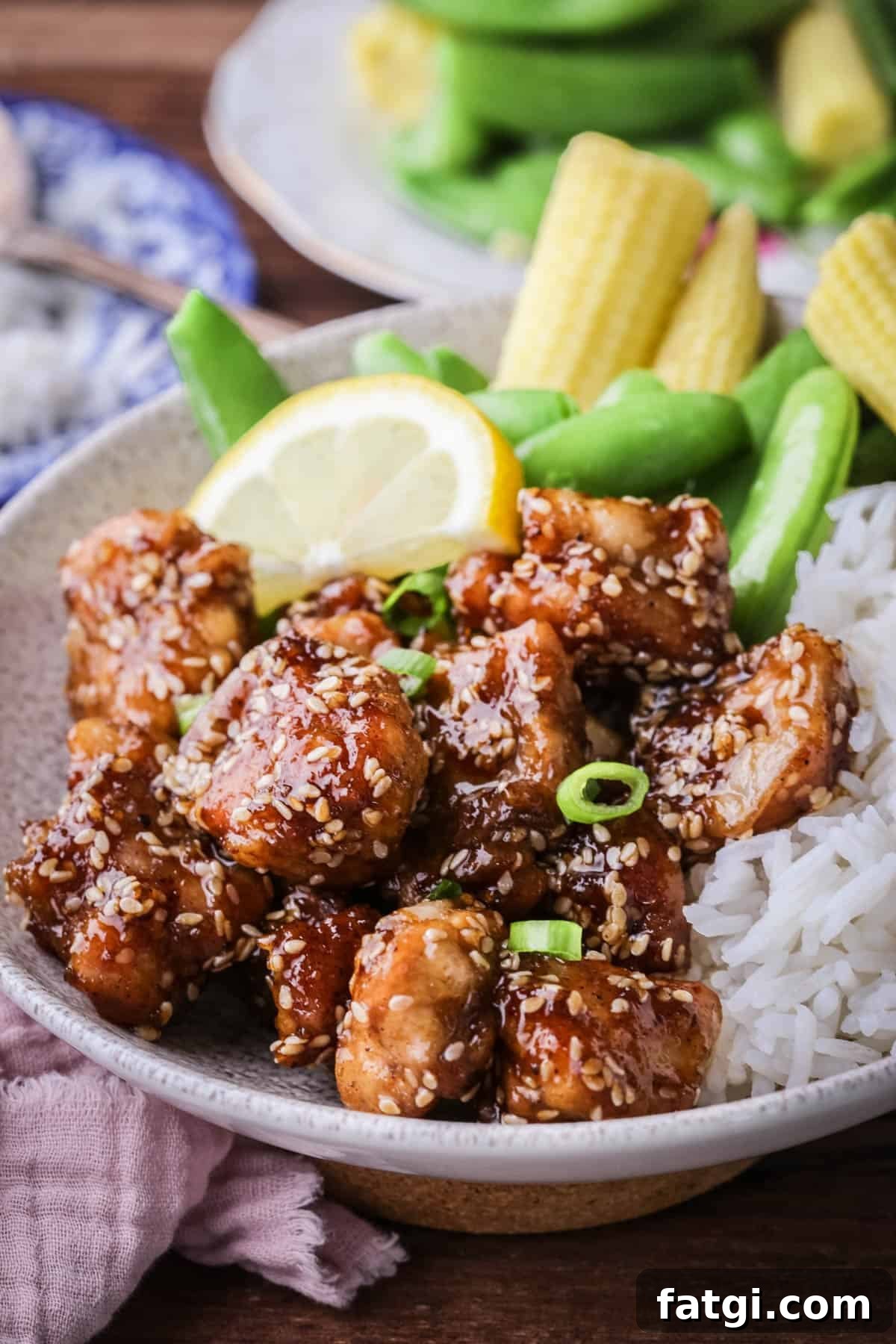 Sticky Lemon Chicken in a bowl with rice and vegetables.