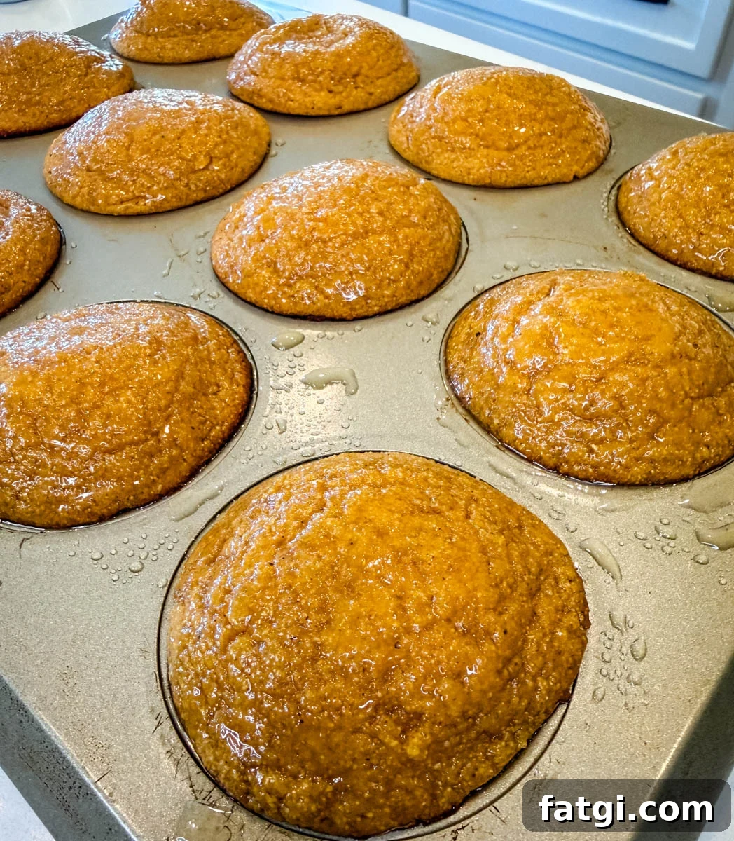 Sweet Potato Honey Cornbread Recipe 8 Freshly baked sweet potato honey cornbread muffins in a muffin pan with a shiny honey butter glaze brushed over the tops.