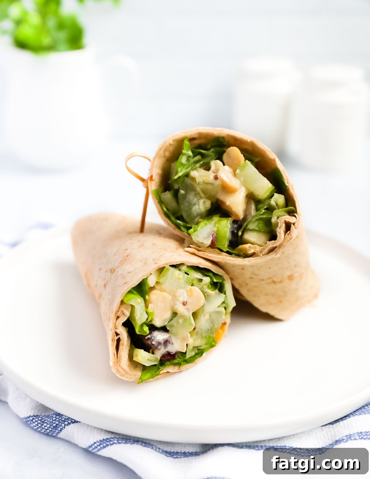 A wrap with fresh vegetables inside it on a white plate.