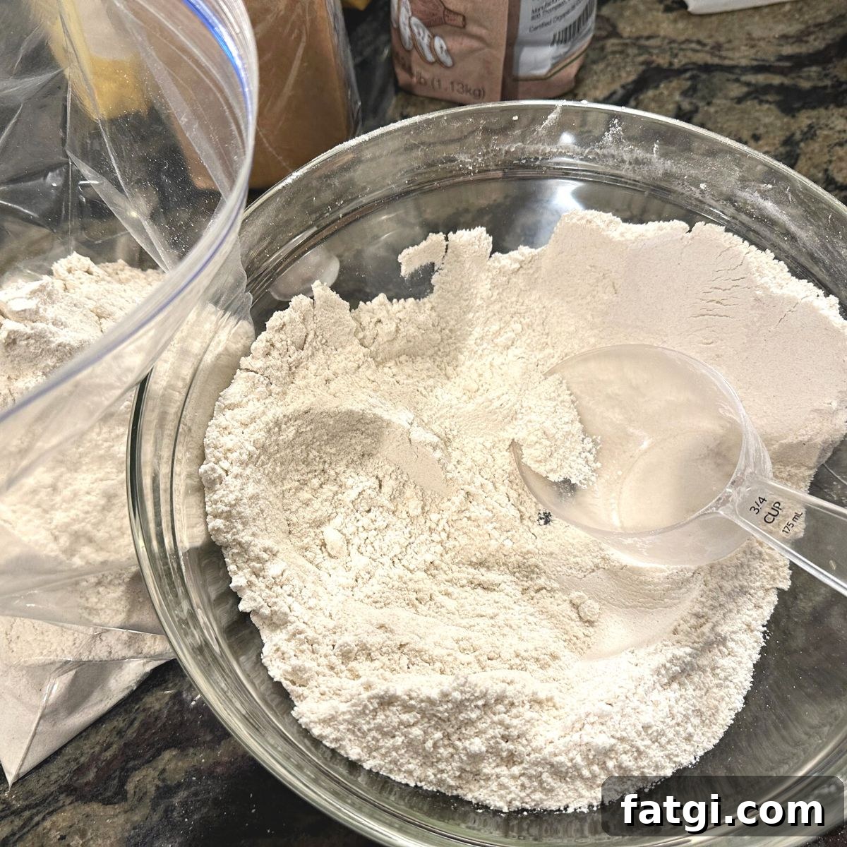 Mixed gluten free flour in a bowl with a plastic measuring scoop.