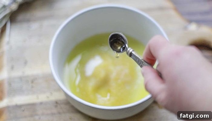 adding apple cider vinegar to a bowl of sugar and oil on a wood cutting board