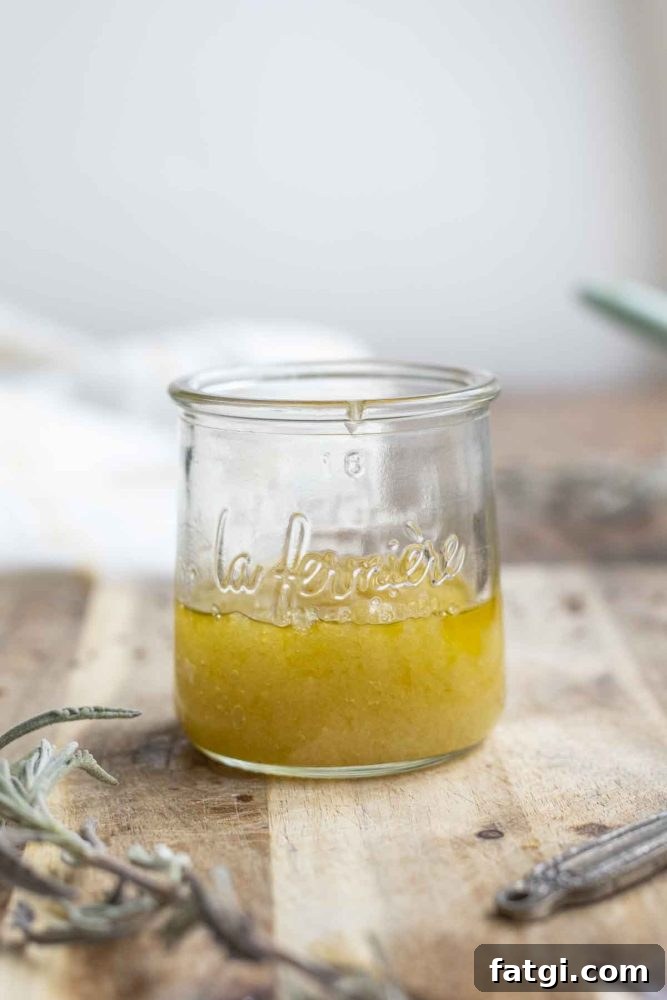 jar of homemade scalp scrub on a wood cutting board surrounded by lavender and a measuring spoon