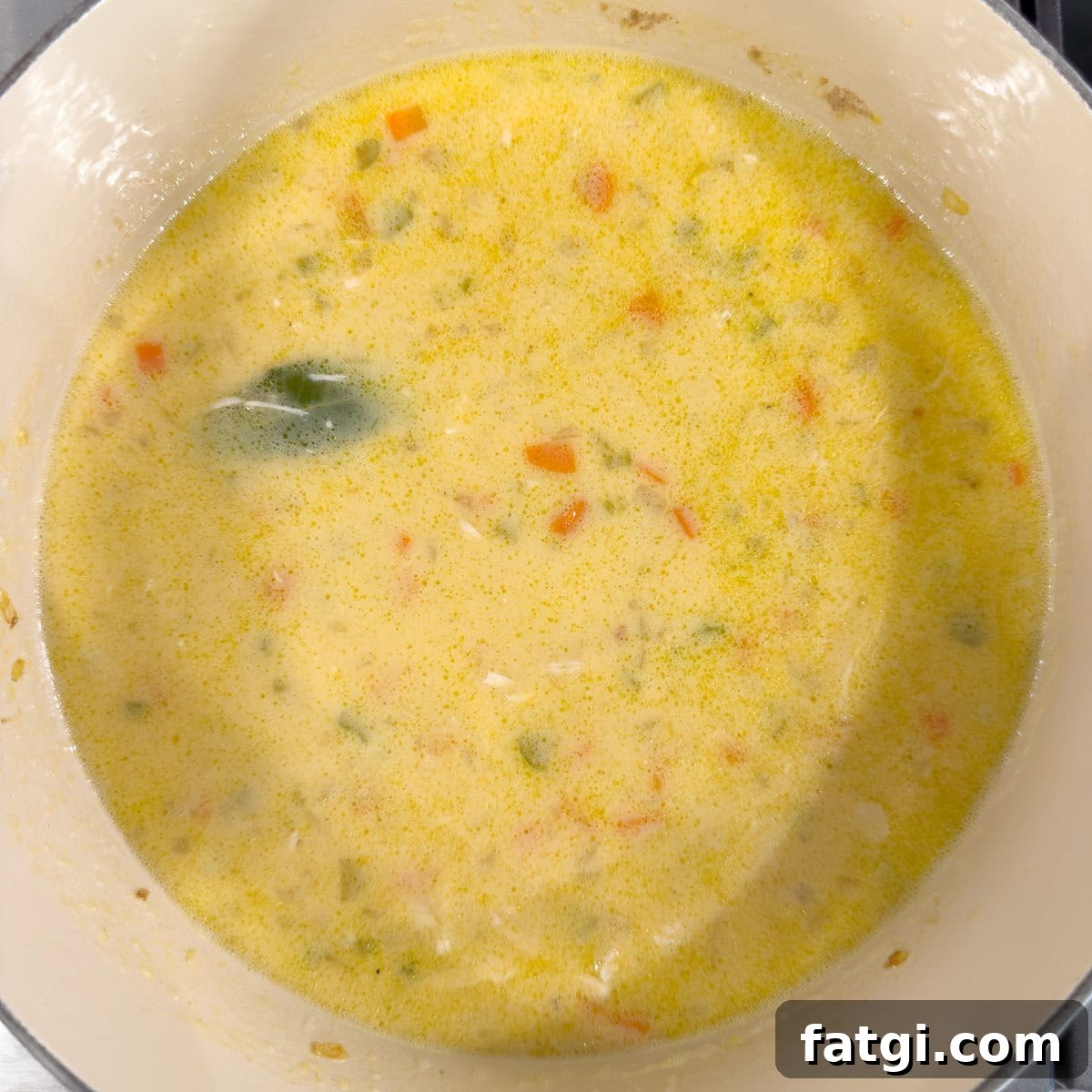 A golden creamy soup being cooked for Greek avgolemono soup.