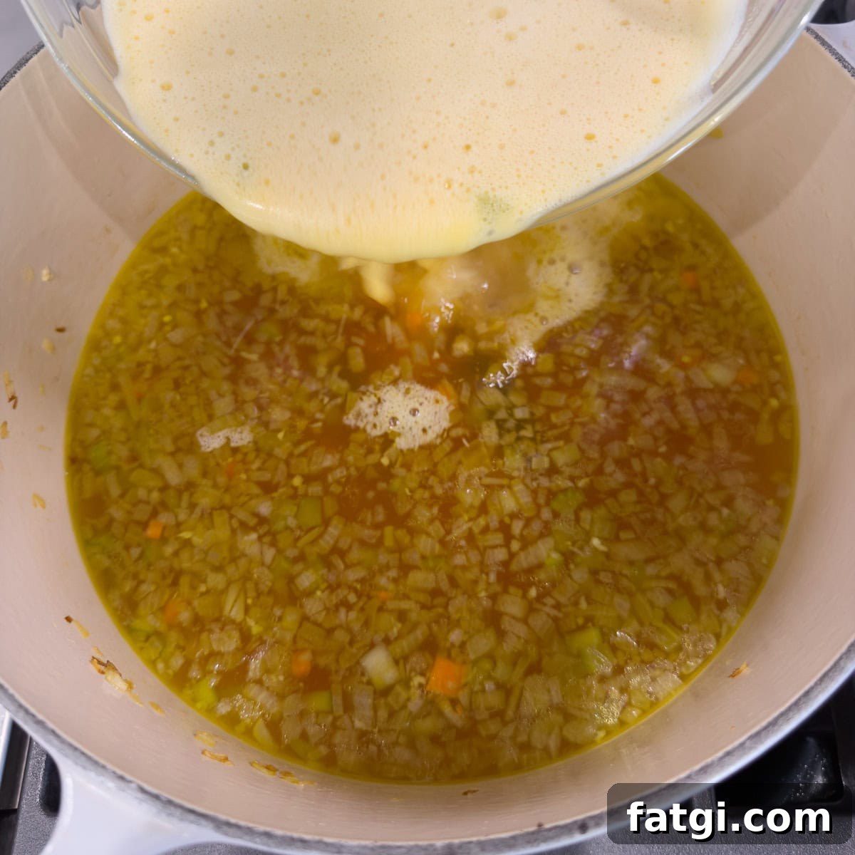 Pouring egg-broth-lemon juice mixture into the sop base.