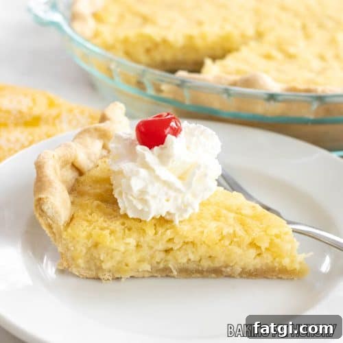 pineapple custard pie sliced and served on small plate with whipped cream and a cherry