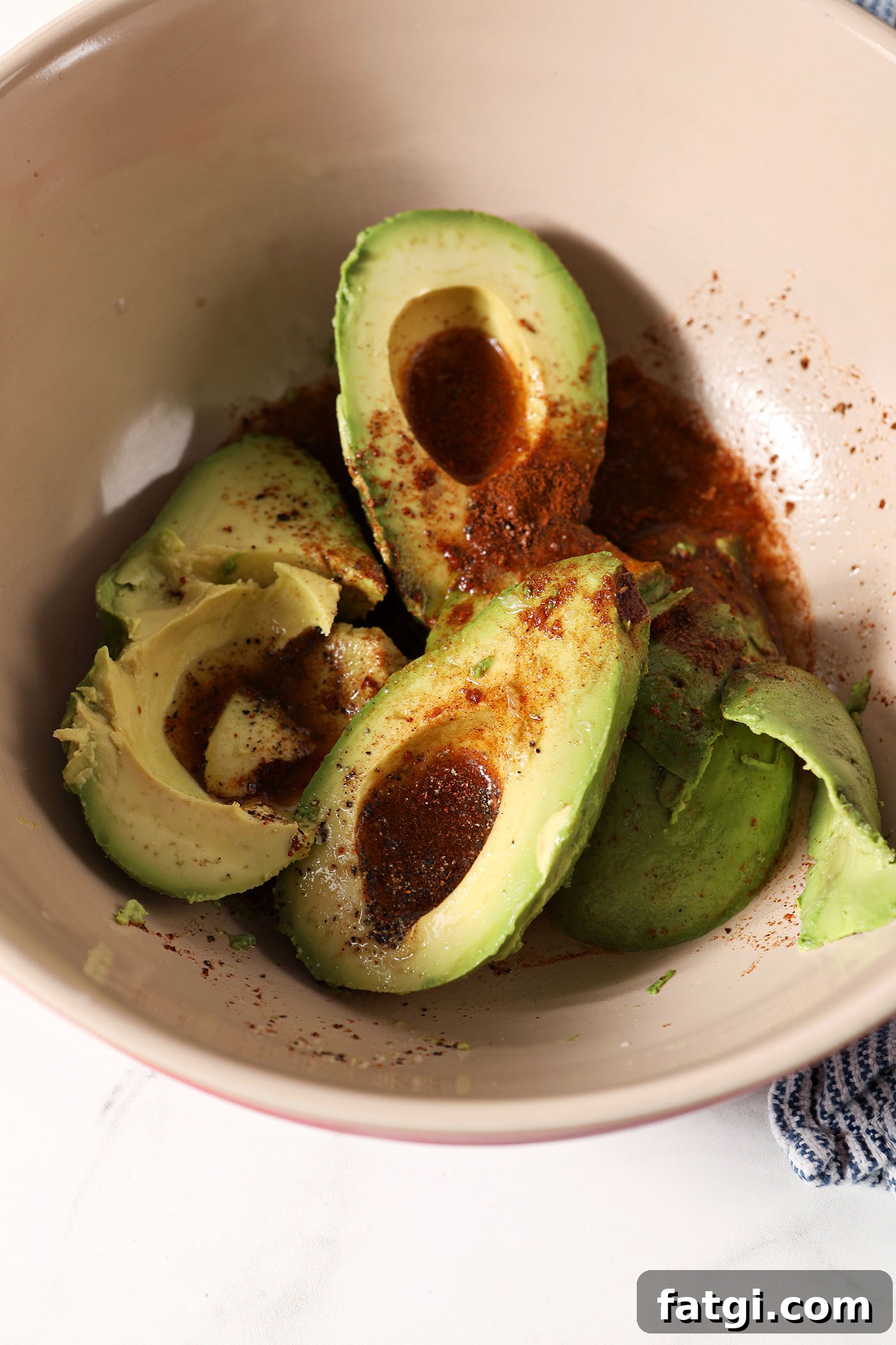 Halved avocados in a bowl seasoned with bbq seasoning