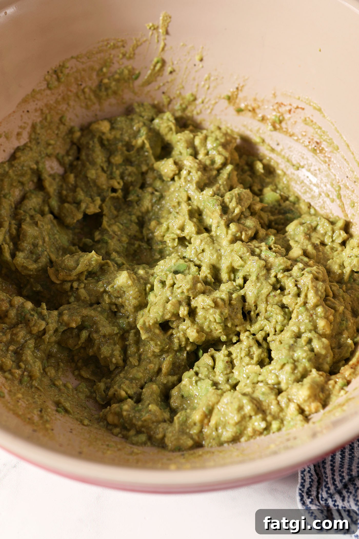 Smashed avocados in a bowl before mixing with coleslaw mix