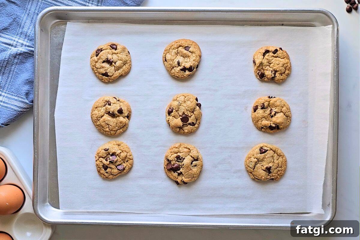 Perfectly baked chocolate chip cookies on a baking tray lined with parchment paper.