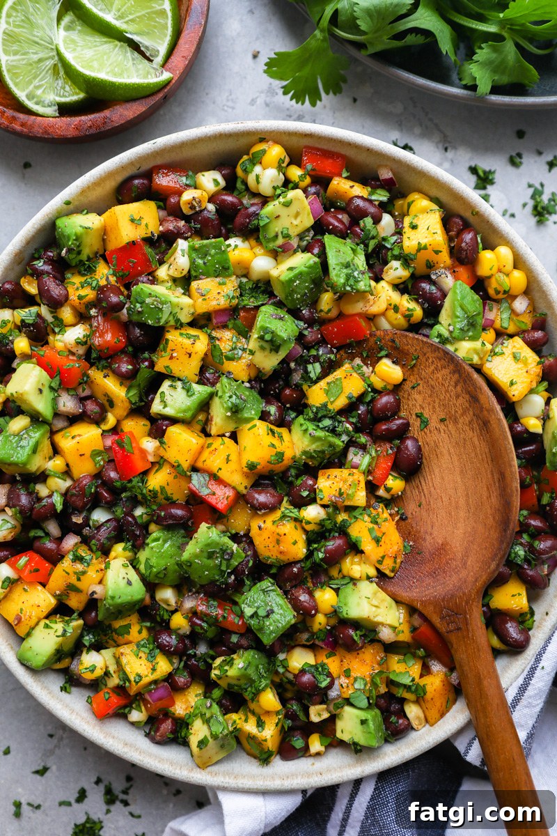 Zesty Black Bean, Mango and Avocado Salad 6 A large servings bowl filled with black bean mango and avocado salad topped with chopped cilantro surrounded by sliced limes and cilantro
