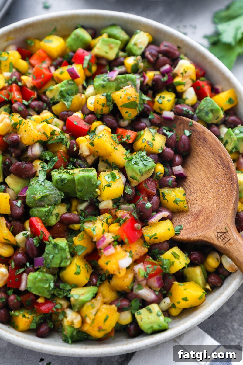 Zesty Black Bean, Mango and Avocado Salad 7 A black bean mango salad topped with diced avocado and cilantro sitting in a large serving bowl